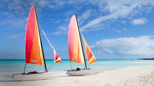 Two-catamarans-with-colorful-sails-wide-open-on-white-sandy-beach-Cayo-Santa-Maria-Cuba.jpg